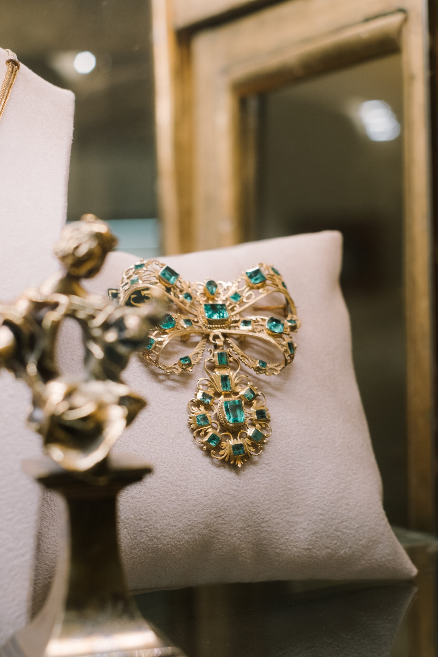 Broche antiguo de oro, esmeraldas y diamantes en el escaparate de una joyería en Sevilla, especialistas en la venta de joyas antiguas.